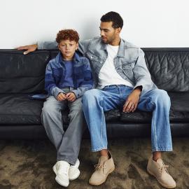 Poika ja mies istuvat farkkuasuissa sohvalla