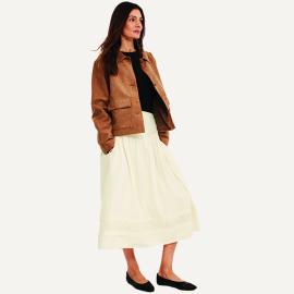 Nainen päällään valkoinen hame ja ruskea takki