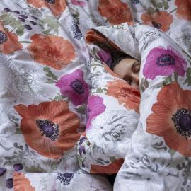 Vaaleapohjainen pussilakanasetti, missä oranssin, keltaisen ja vaaleanpunaisen värisiä Leinikki kukkia